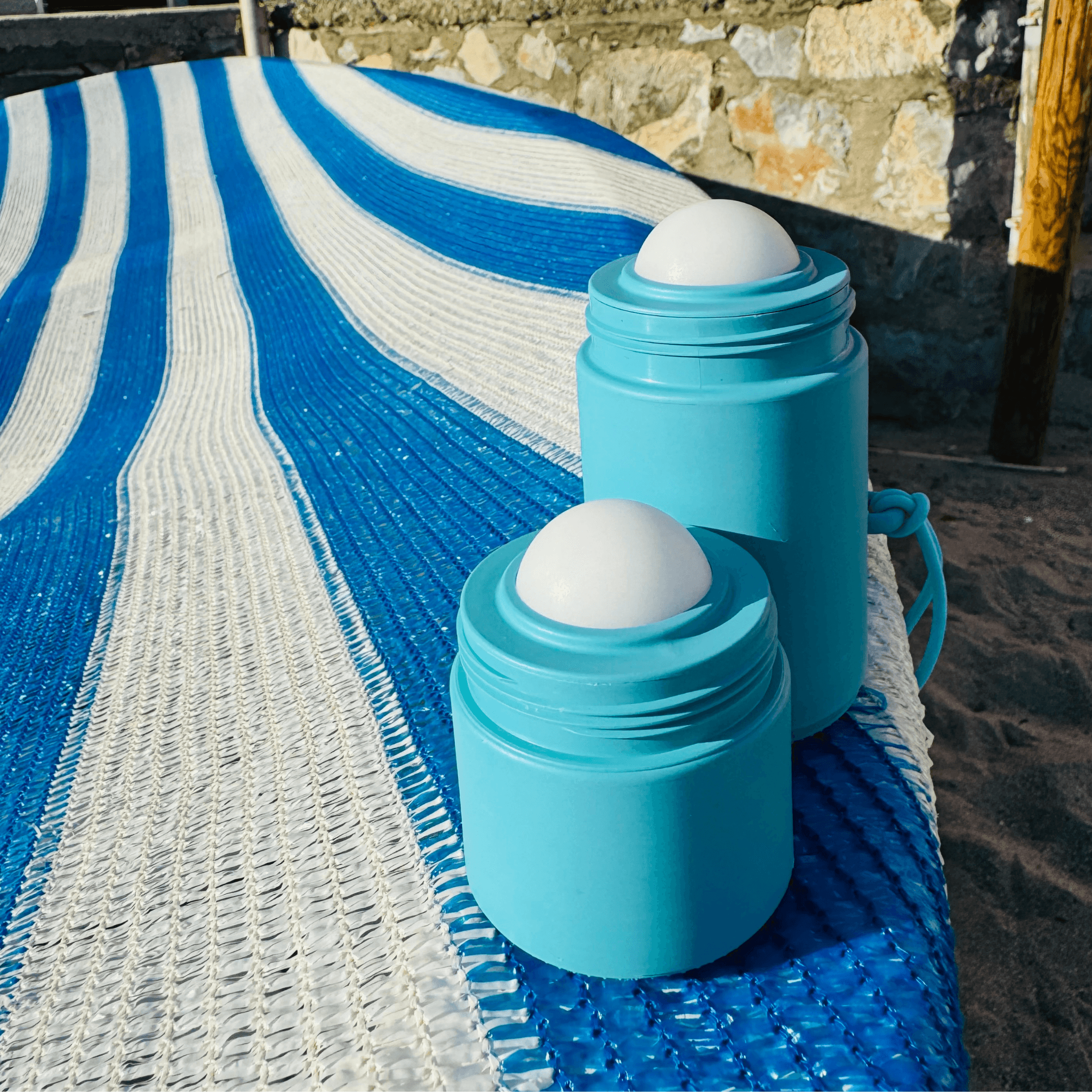 Two different sized blue refillable roll-on travel applicators on striped towel