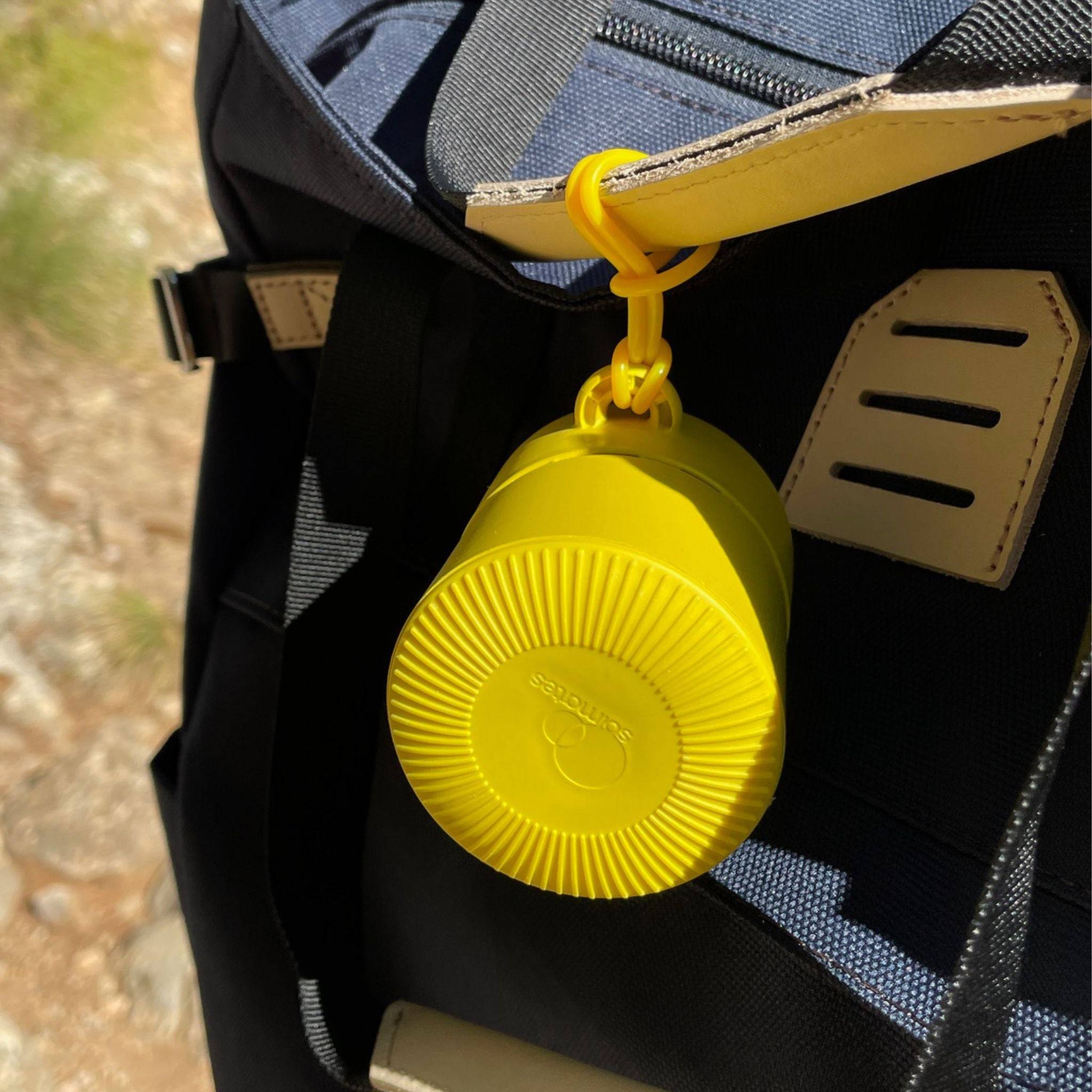 Yellow refillable roll-on travel applicator attached to a backpack