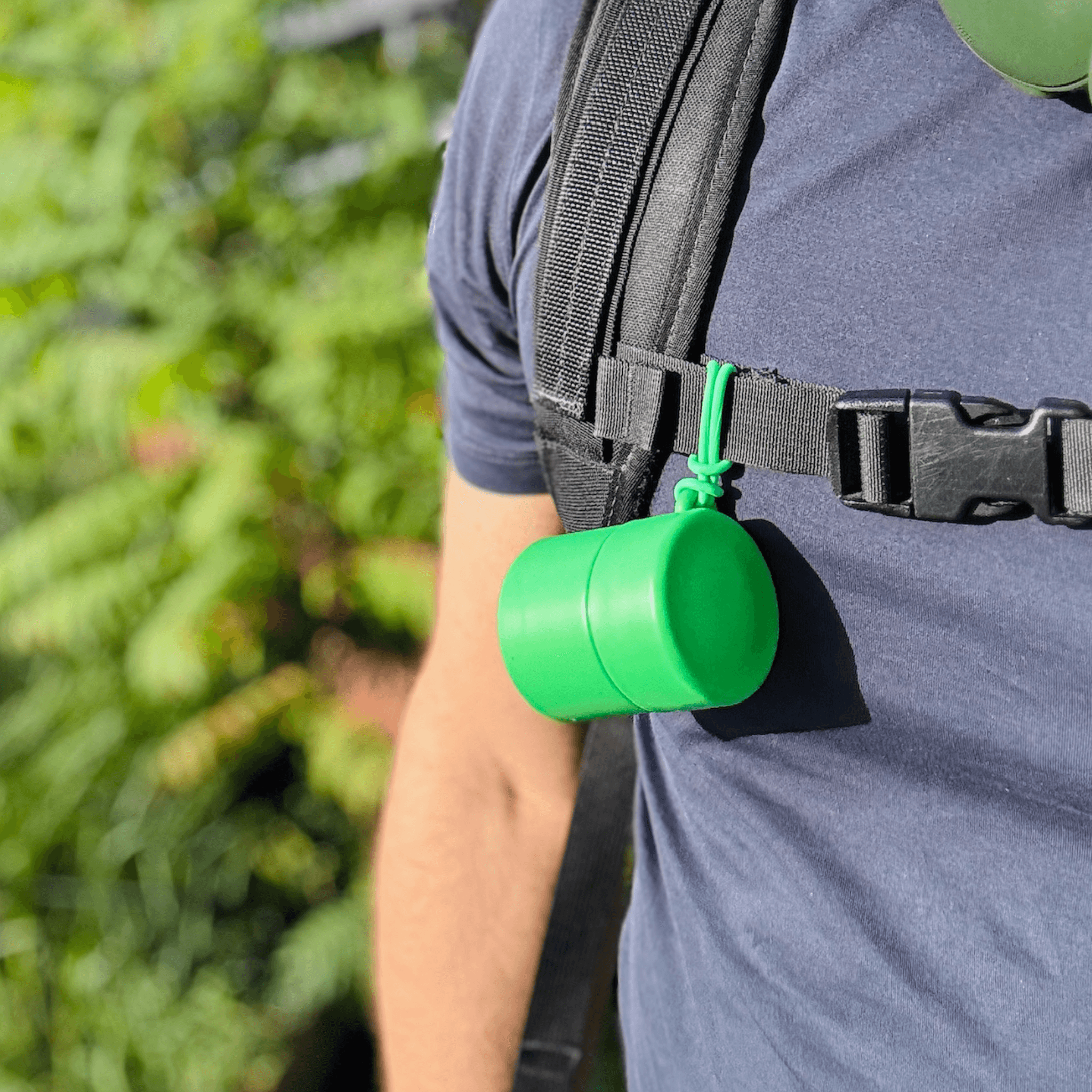 Green refillable roll-on travel applicator attached to backpack on man